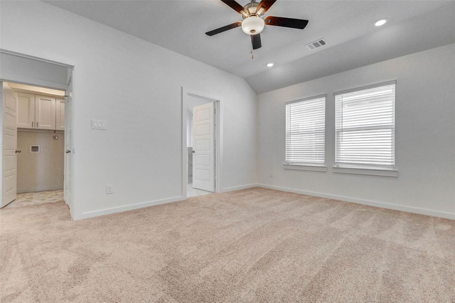 Spacious primary bedroom with plush carpet, high ceiling, ceiling fan, recessed lighting, and two windows for natural light. This private retreat offers plenty of room for a full bedroom furniture setup and a comfortable place to unwind.