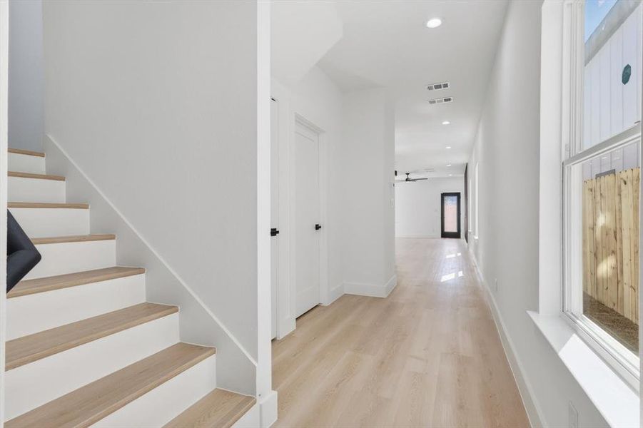 Entryway featuring light wood-finish flooring, white walls, recessed lighting, and a prominent staircase with wood treads Entryway featuring light wood-finish flooring, white walls, recessed lighting, and a prominent staircase with wood treads