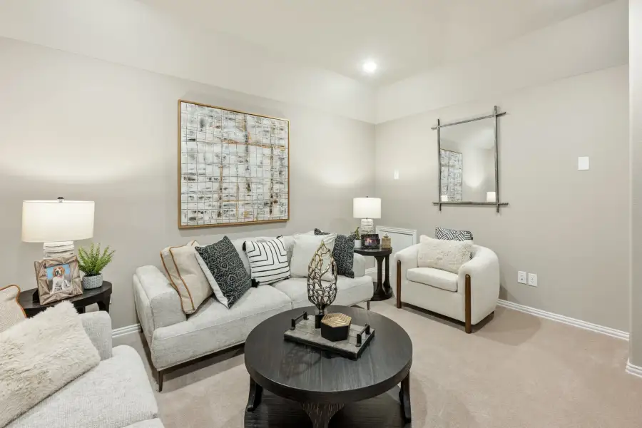 Living room with light gray sofa, round dark coffee table, accent chair, and large wall art on beige carpet
