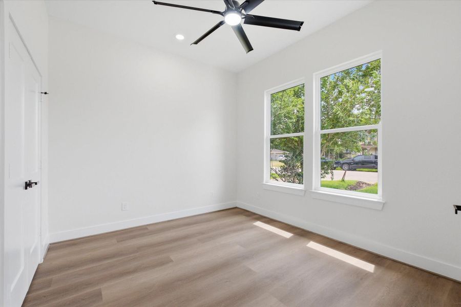 This versatile room located off the entrance is filled with natural light from two large front-facing windows looking out onto the mature trees. Complete with a sleek black ceiling fan, recessed lighting, and wood-style vinyl flooring, it serves perfectly as a home office or additional bedroom. This versatile room located off the entrance is filled with natural light from two large front-facing windows looking out onto the mature trees. Complete with a sleek black ceiling fan, recessed lighting, and wood-style vinyl flooring, it serves perfectly as a home office or additional bedroom.