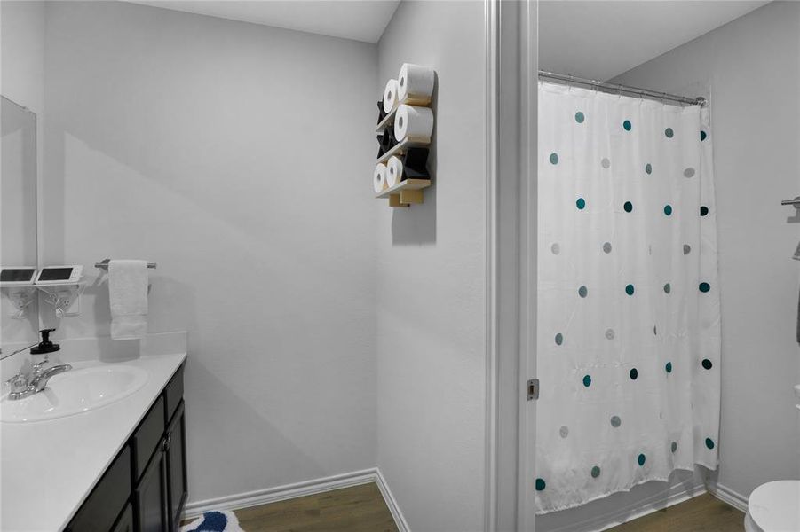 Bathroom featuring dark wood-style flooring, vanity, and shower / tub combo