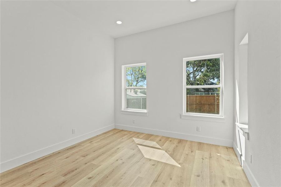 Empty room with light wood finished floors and recessed lighting