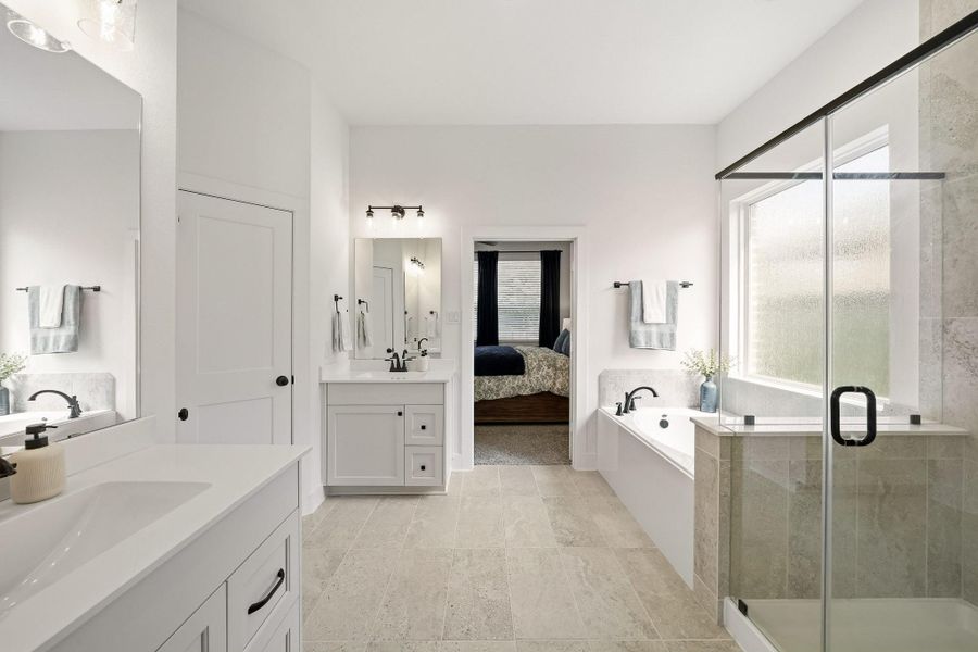 The separate shower creates a refined spa-like experience with a sleek frameless glass entry and beautifully tiled surround extending to the ceiling, delivering a sophisticated, custom-inspired finish.