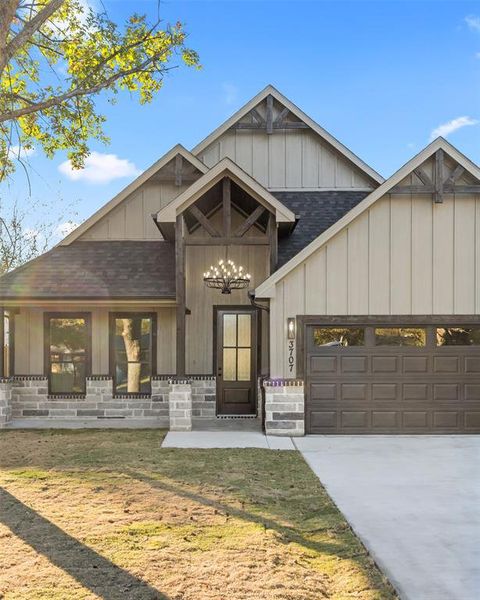 View of front facade with roof with shingles, board and batten siding, an attached garage, and driveway View of front facade with roof with shingles, board and batten siding, an attached garage, and driveway