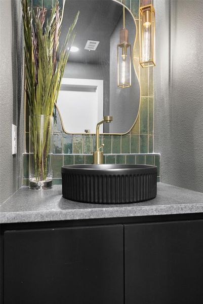 Bathroom featuring vanity, a textured wall, and decorative backsplash