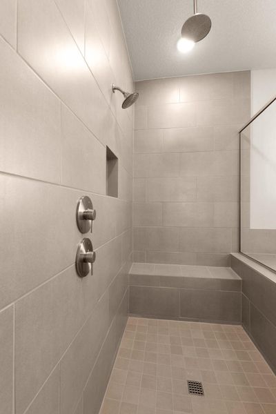 Full bath featuring a textured ceiling and tiled shower
