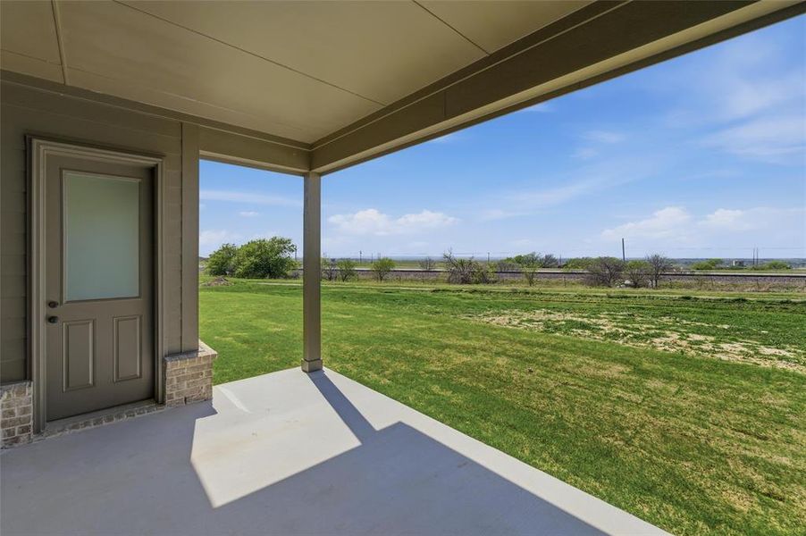 View of green lawn with a patio area and a rural view View of green lawn with a patio area and a rural view