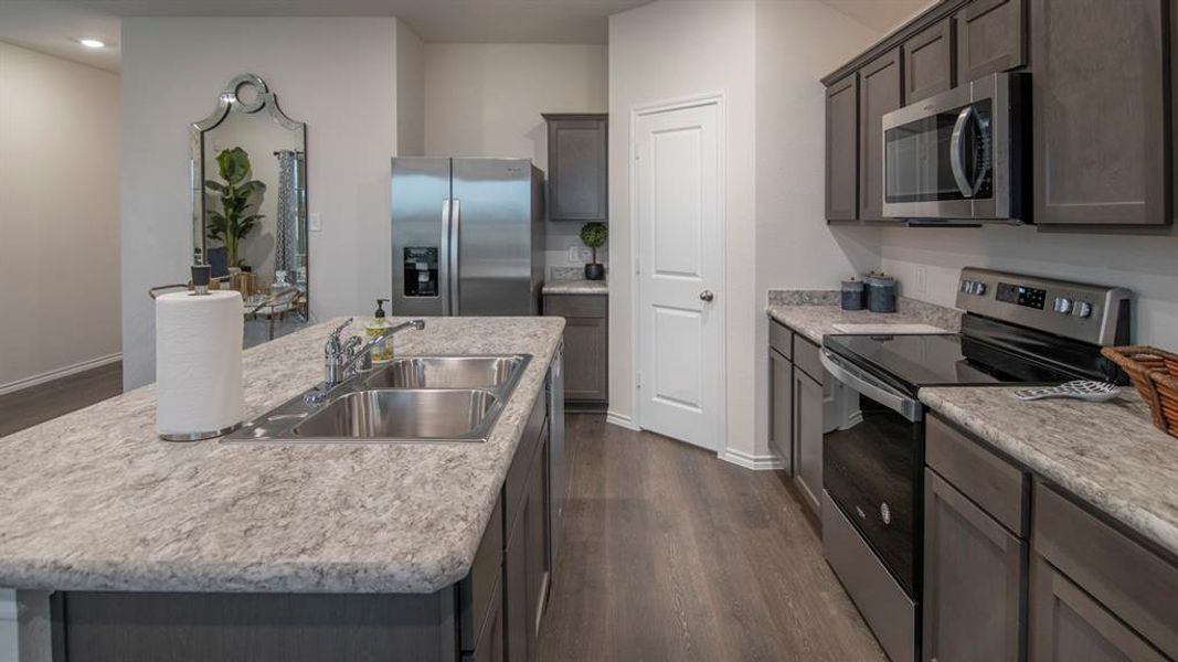 Kitchen with stainless steel appliances, dark wood finished floors, a center island with sink, dark wood finish cabinetry, and recessed lighting