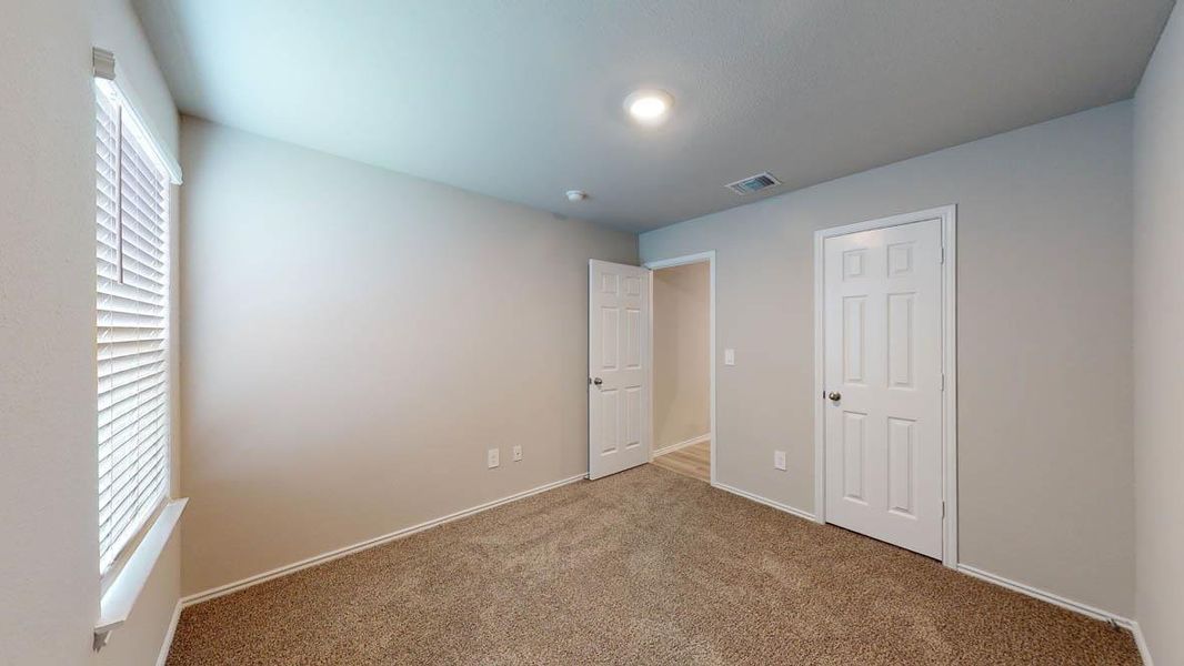 A well-lit bedroom with plush carpeting, offering a cozy retreat with ample natural light. A well-lit bedroom with plush carpeting, offering a cozy retreat with ample natural light.