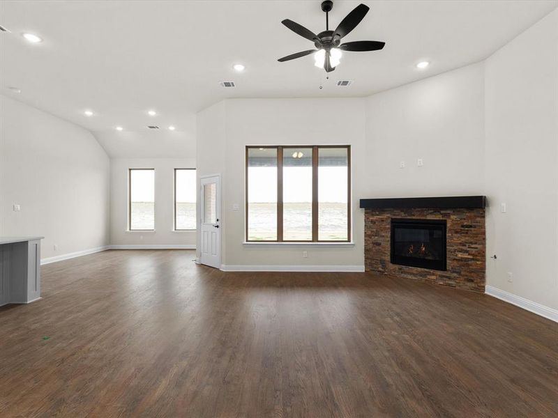Unfurnished living room featuring recessed lighting, a stone fireplace, dark wood-type flooring, and a ceiling fan