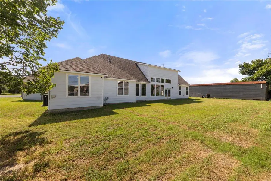 Rear view of house featuring a shingled roof and a yard Rear view of house featuring a shingled roof and a yard