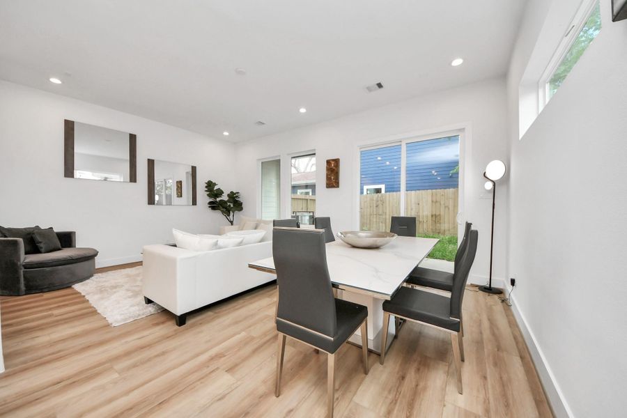 Discover a stylish dining area seamlessly integrated into a bright, modern living space, featuring sleek furnishings and abundant natural light for a welcoming atmosphere.