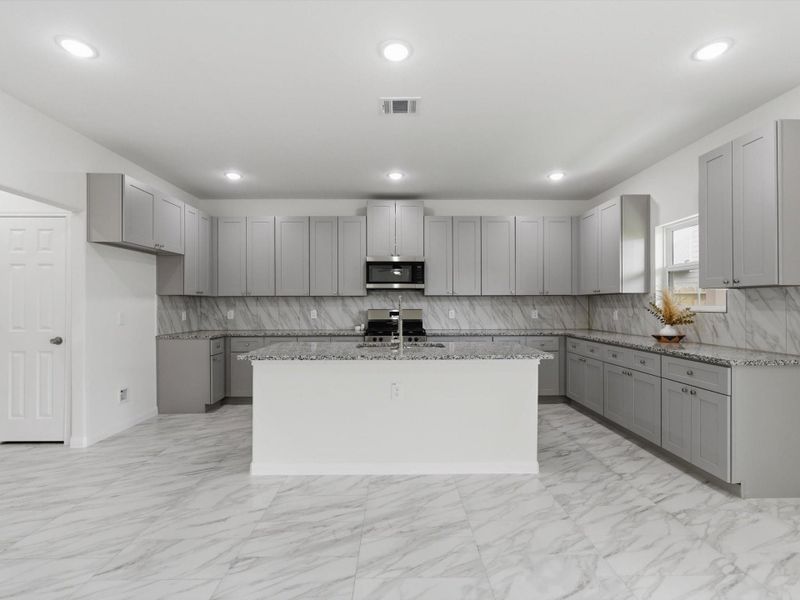 Sleek and functional, this beautifully appointed kitchen showcases granite counters, stainless steel appliances, soft-close cabinets, and a generous walk-in pantry.
