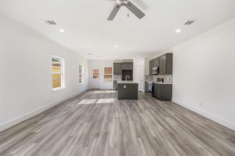 Unfurnished living room with light wood-type flooring, a ceiling fan, and recessed lighting