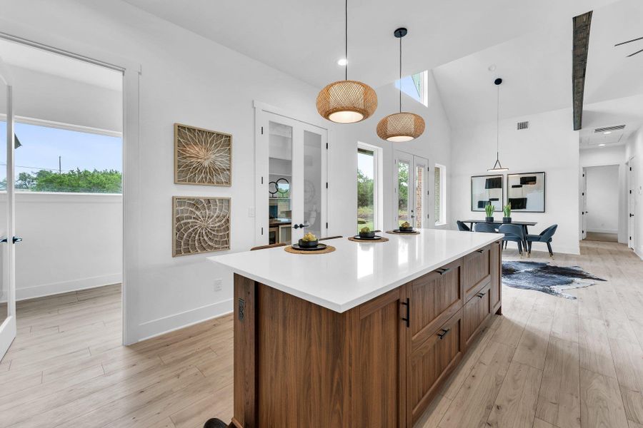 A grand kitchen island with gleaming white countertops serves as the focal point of this open-concept living space. A grand kitchen island with gleaming white countertops serves as the focal point of this open-concept living space.