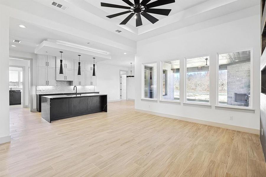 Kitchen featuring a center island with sink, white cabinets, sink, ceiling fan, and decorative light fixtures