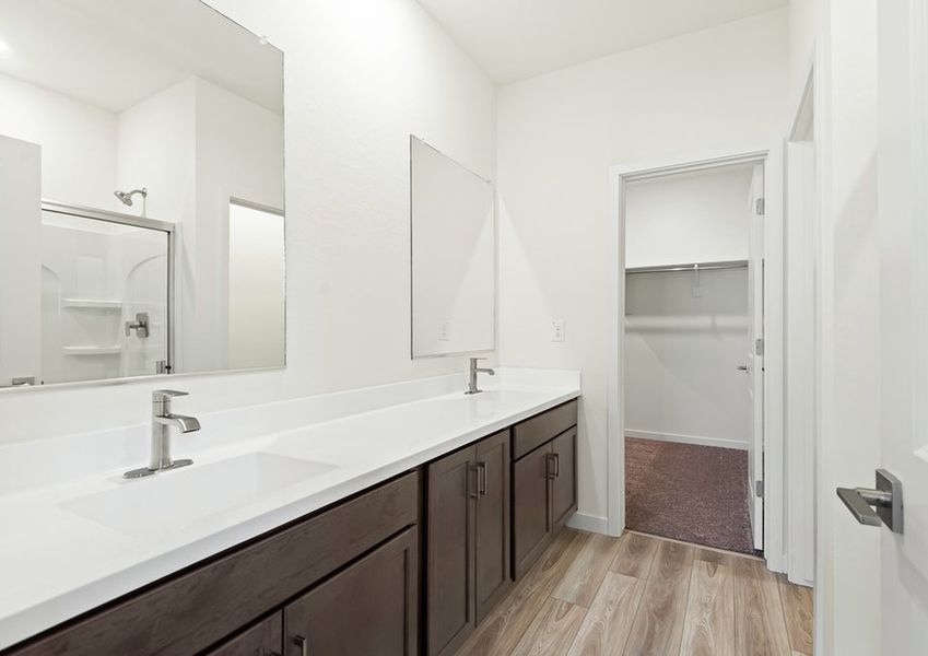 The master bathroom features dual-vanity sinks and a glass-enclosed shower.