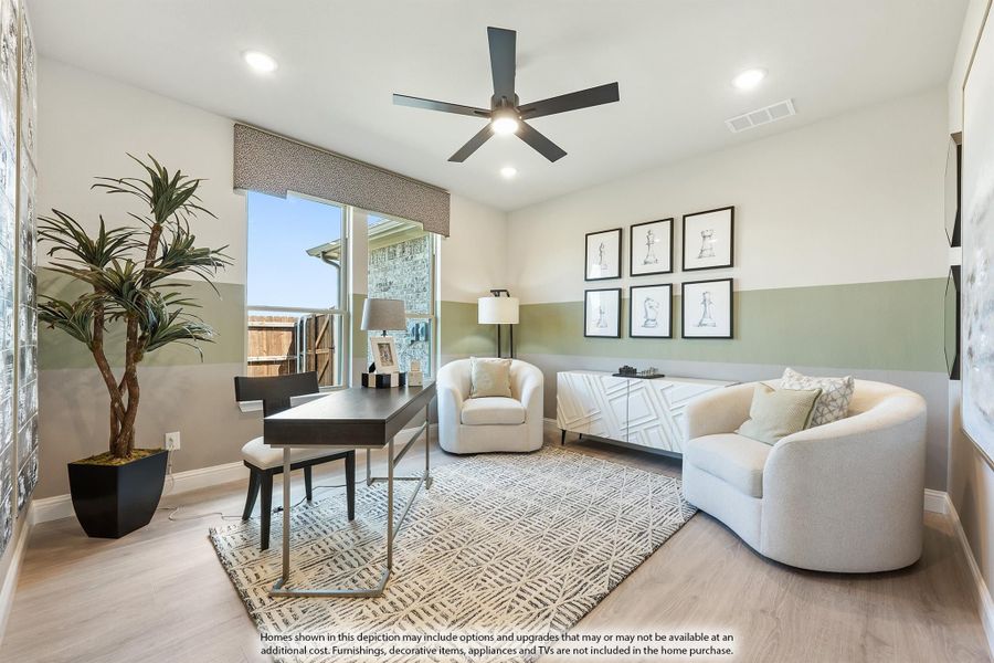 Home office with desk, seating area, ceiling fan, and two-tone green accent walls on hardwood floors