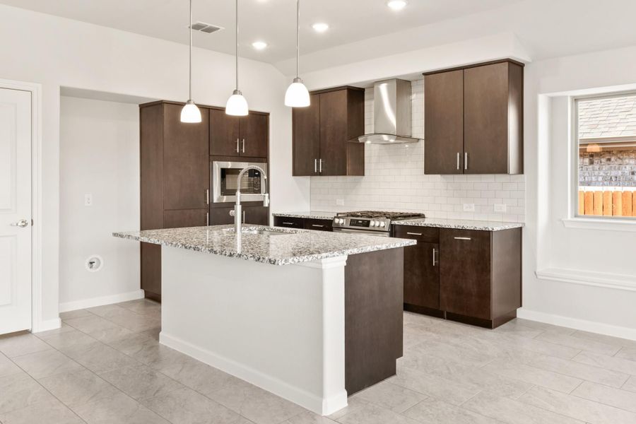 Kitchen with dark brown cabinets, granite island, stainless steel appliances, and white subway tile backsplash Kitchen with dark brown cabinets, granite island, stainless steel appliances, and white subway tile backsplash