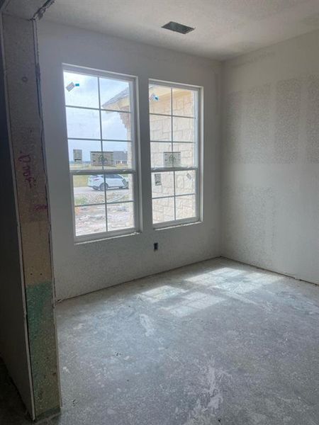Room undergoing construction featuring two large windows, a ceiling vent, and unfinished drywall
