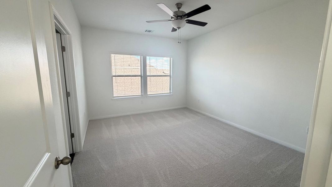 A well-lit bedroom features plush carpeting and a modern ceiling fan, offering a comfortable personal retreat. A well-lit bedroom features plush carpeting and a modern ceiling fan, offering a comfortable personal retreat.