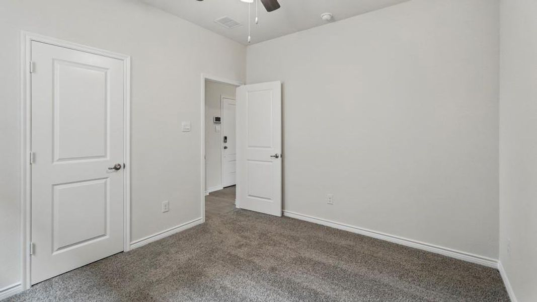 Unfurnished bedroom with dark colored carpet and ceiling fan