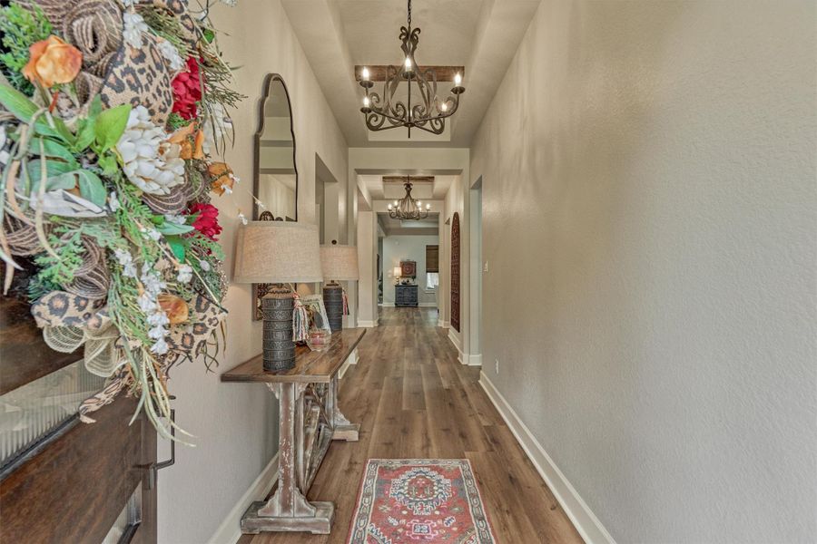 Impressive entryway featuring rich wood-plank flooring, elegant chandeliers, and striking wood beam ceiling accents set the tone for the home's sophisticated design. Impressive entryway featuring rich wood-plank flooring, elegant chandeliers, and striking wood beam ceiling accents set the tone for the home's sophisticated design.