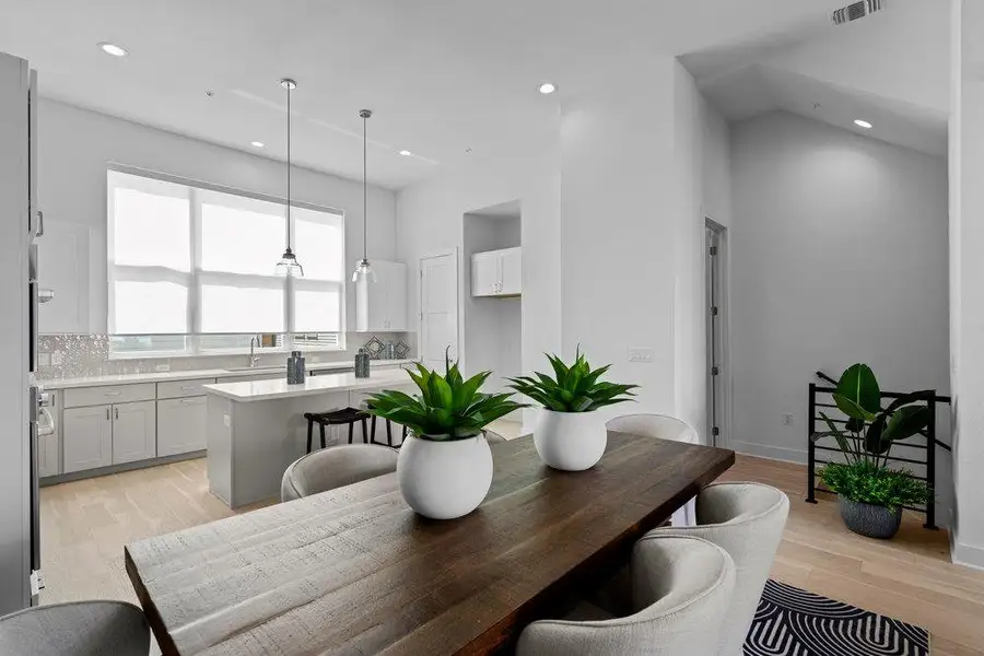 Gleaming hardwood floors and high vaulted ceilings elevate this open dining and kitchen space. Gleaming hardwood floors and high vaulted ceilings elevate this open dining and kitchen space.
