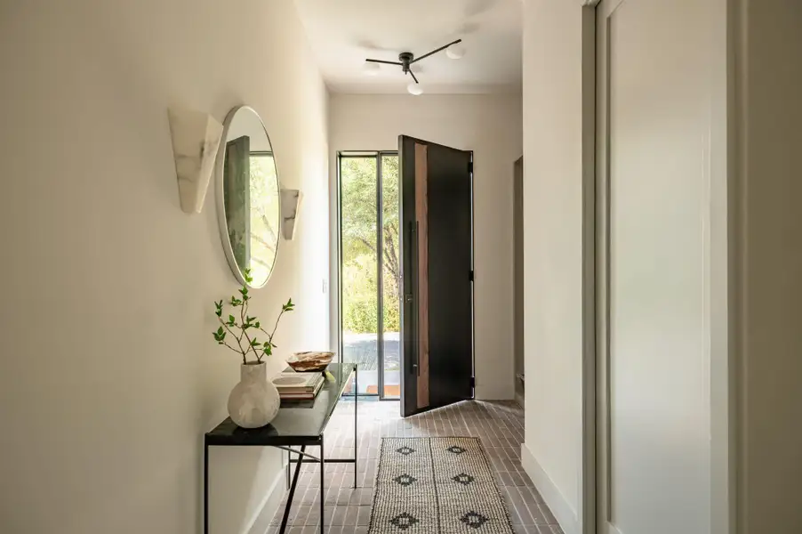 A welcoming entryway features durable tile flooring and a modern pivot front door. A welcoming entryway features durable tile flooring and a modern pivot front door.