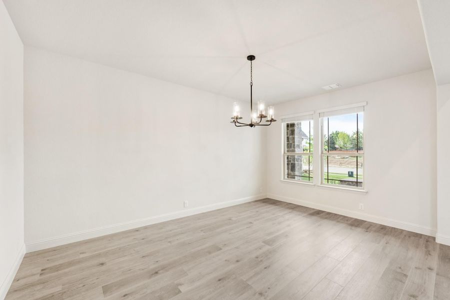 Empty dining room with light wood floors, chandelier, and double windows Empty dining room with light wood floors, chandelier, and double windows