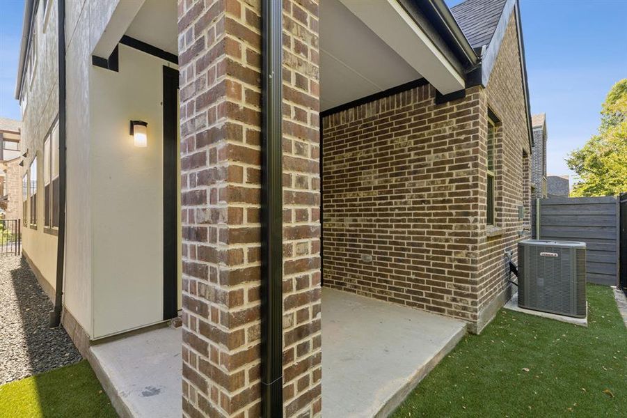 View of side of property with fence, central AC unit, and brick siding