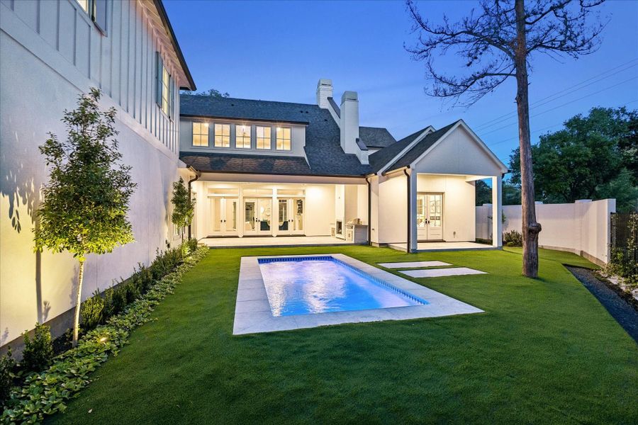 Another view highlights the covered outdoor living areas overlooking the heated pool & turf yard. Fenced grounds & landscape lighting create a beautifully designed outdoor setting.