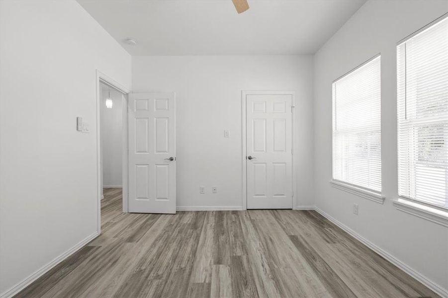 Unfurnished bedroom with a ceiling fan, wood finished floors, and baseboards