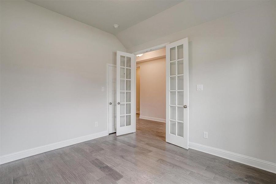 Spare room with french doors, lofted ceiling, and light hardwood / wood-style flooring