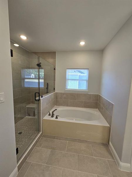 Bathroom with shower with separate bathtub and tile patterned floors