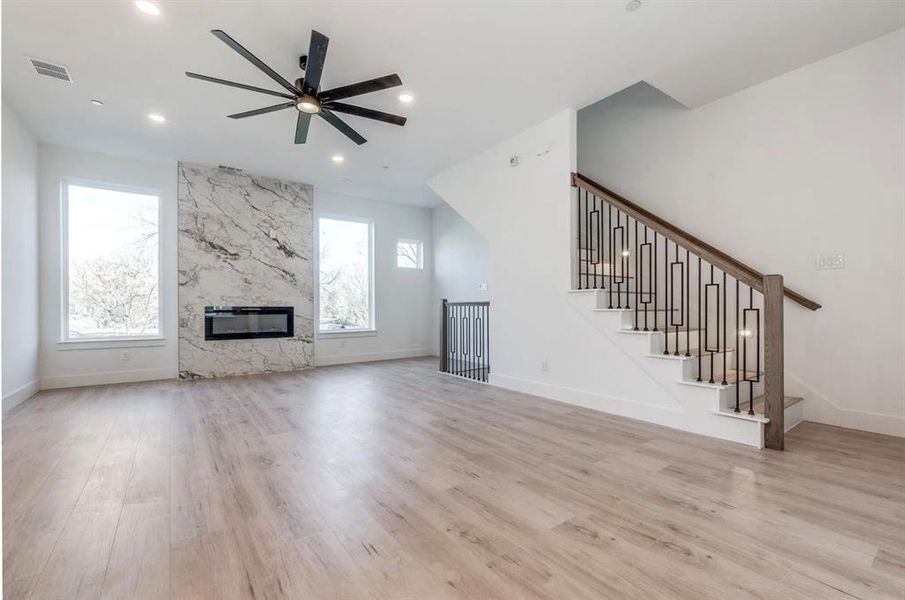 Unfurnished living room with light wood-type flooring, ceiling fan, and a fireplace