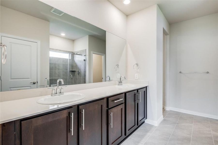 Bathroom featuring walk in shower, tile patterned floors, and dual bowl vanity