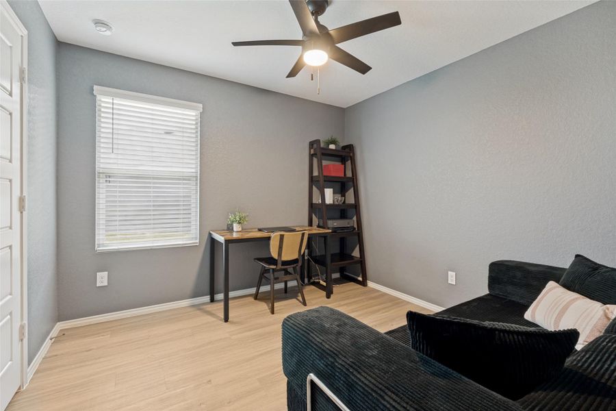 Functional home office or cozy den features a bright window and a ceiling fan for comfort.