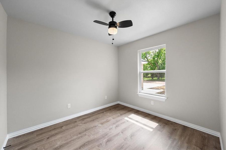 Neutral-toned room with wood-finish flooring, white baseboards, and a single window with white trim