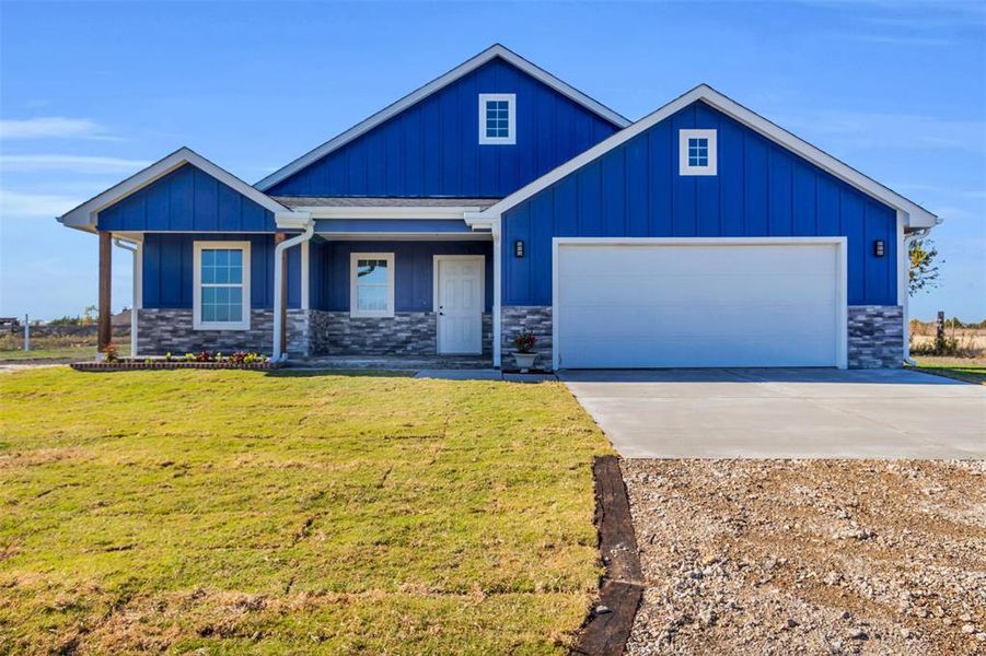 View of front of home with driveway, an attached garage, stone siding, a front lawn, and board and batten siding View of front of home with driveway, an attached garage, stone siding, a front lawn, and board and batten siding