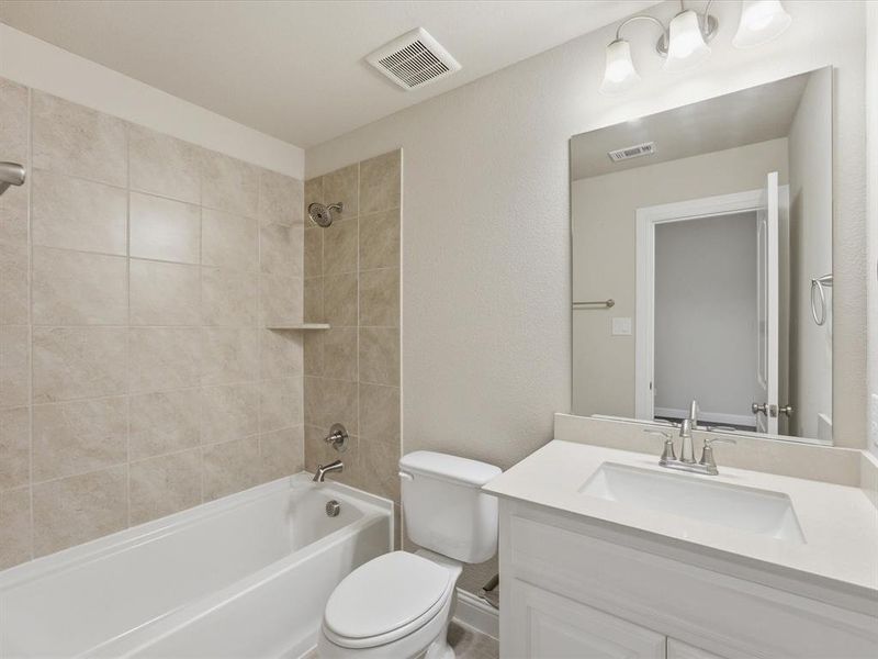 Full bathroom featuring a white tub, light-toned tile shower surround, chrome fixtures, white vanity with integrated sink, and wall-mounted mirror