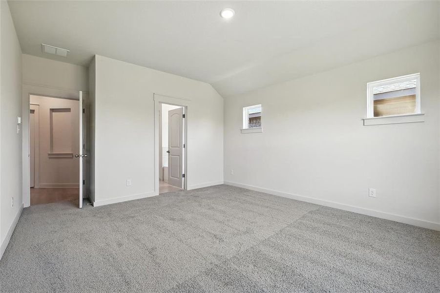 Unfurnished bedroom featuring light carpet and lofted ceiling