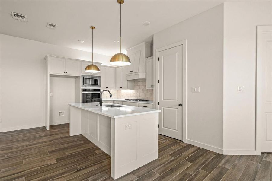 Kitchen with a sink, appliances with stainless steel finishes, dark wood finished floors, white cabinetry, and light countertops