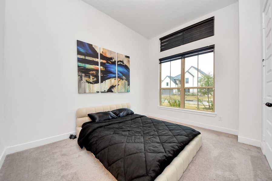 Main-level 2nd bedroom with oversized window and clean, modern design.