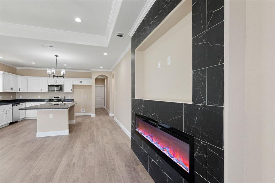 Kitchen with arched walkways, stainless steel appliances, visible vents, white cabinetry, and light wood-type flooring