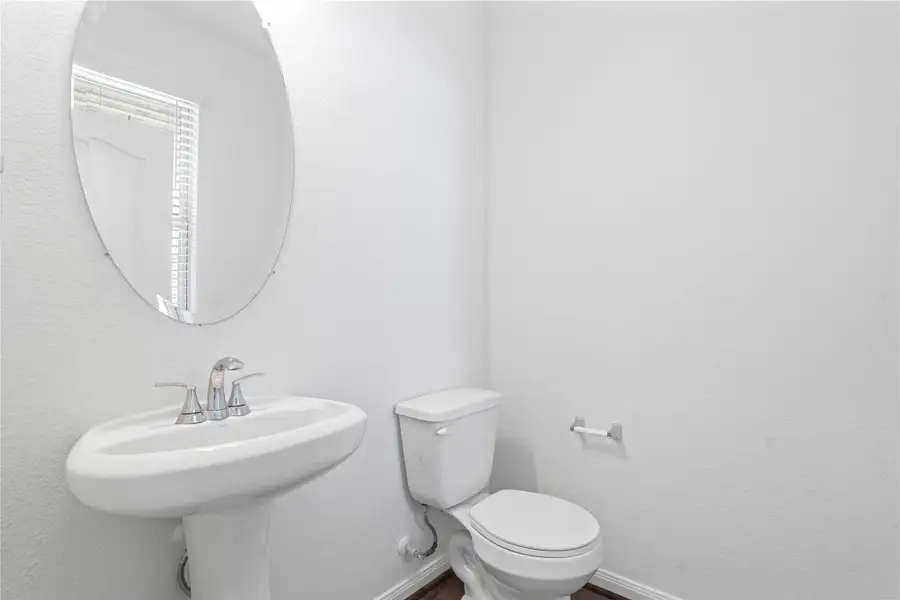 The powder room on the first floor includes a pedestal sink, mirror, and toilet to conveniently meet your needs.