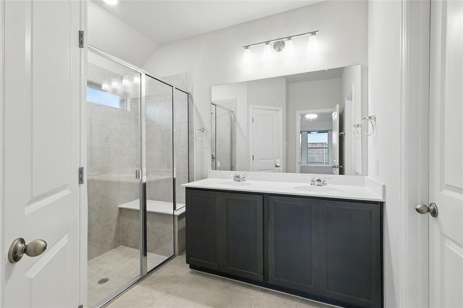 Bathroom featuring healthy amount of natural light, double vanity, a stall shower, and light tile patterned flooring