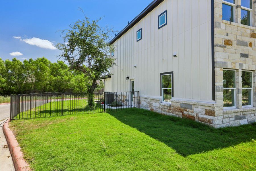 A fenced lawn frames this modern exterior showcasing board and batten siding paired with stone accents.