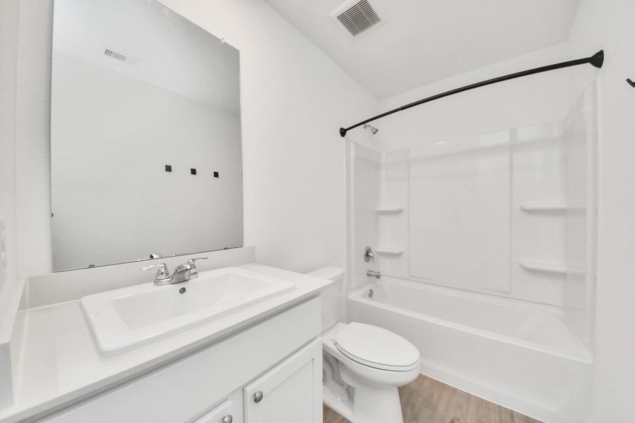 Full bathroom with vanity and tub/shower combo.