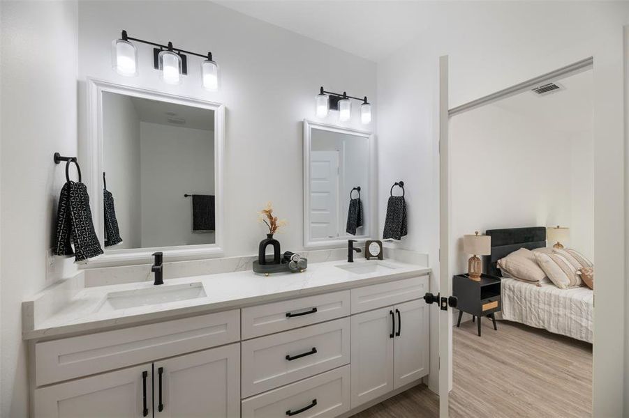 Bathroom featuring double vanity, light wood-type flooring, and connected bathroom Bathroom featuring double vanity, light wood-type flooring, and connected bathroom